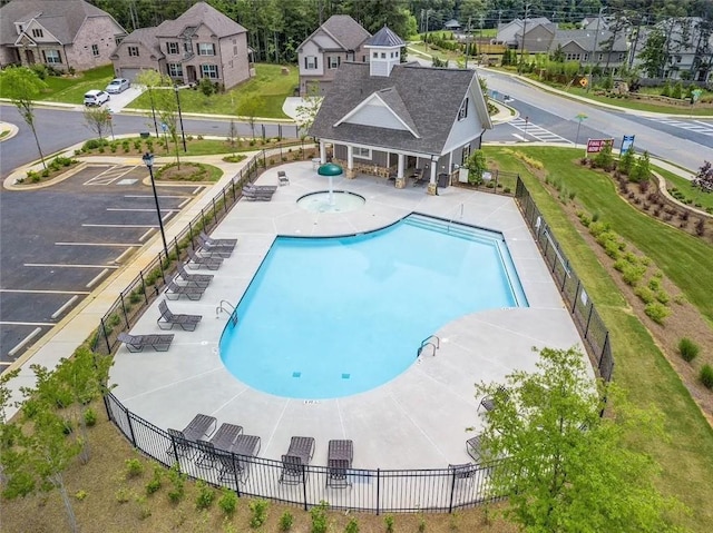 community pool featuring a patio, fence, and a residential view