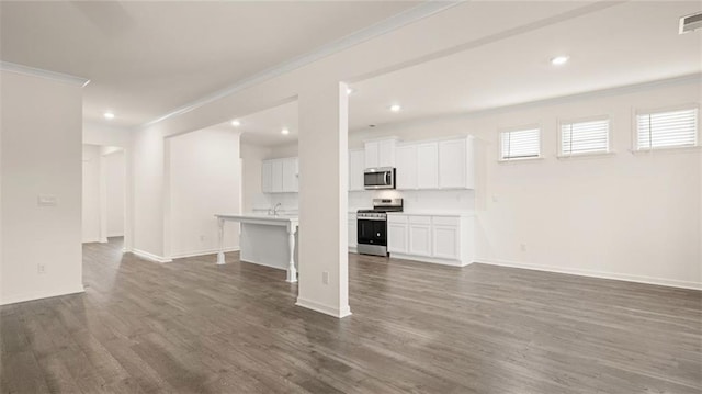 989 Blue Juniper Cir, Loganville, GA 30052 - unfurnished living room featuring crown molding, recessed lighting, dark wood-type flooring, baseboards, and visible vents
