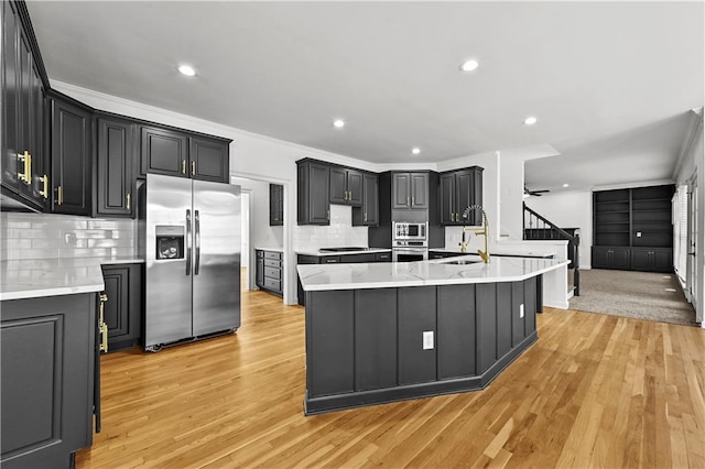 kitchen featuring a sink, light wood-type flooring, appliances with stainless steel finishes, and light countertops