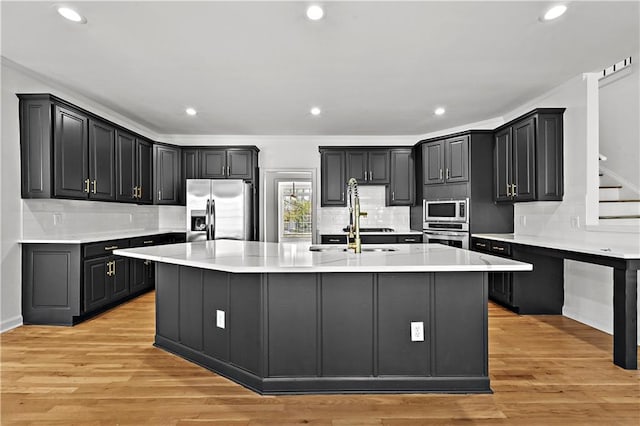 kitchen featuring a spacious island, light wood-style flooring, a sink, stainless steel appliances, and light countertops