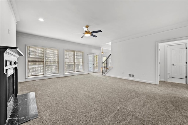 unfurnished living room featuring stairway, crown molding, carpet floors, and a premium fireplace