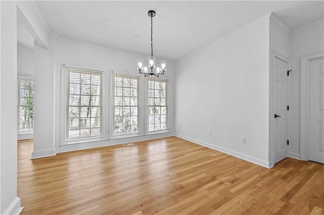 unfurnished dining area with a notable chandelier, baseboards, light wood-style floors, and ornamental molding