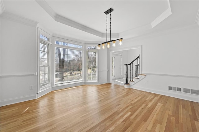 unfurnished dining area with crown molding, baseboards, stairway, wood finished floors, and a raised ceiling