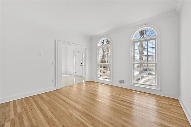 empty room with visible vents, baseboards, wood finished floors, and ornamental molding