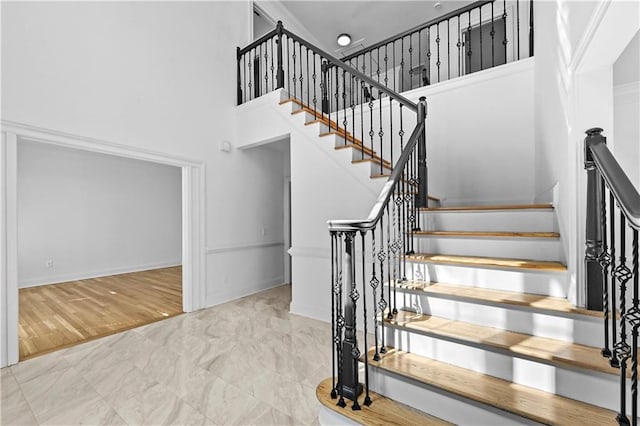 stairway featuring baseboards and a towering ceiling