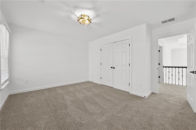 unfurnished bedroom with a closet, carpet flooring, baseboards, and visible vents