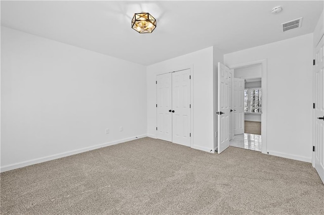 unfurnished bedroom featuring visible vents, carpet floors, baseboards, and a closet