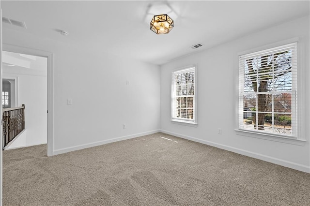 unfurnished room with visible vents, baseboards, and carpet