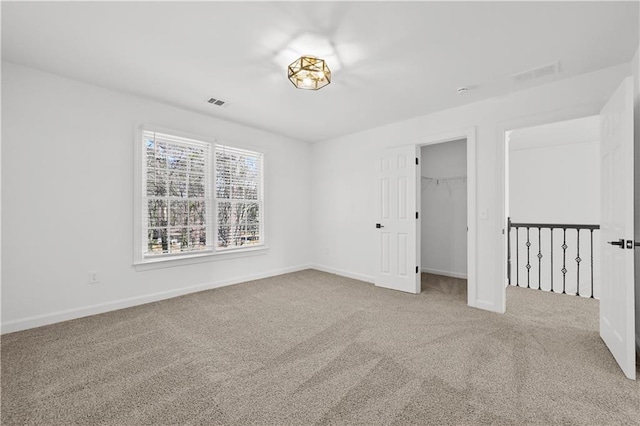 empty room with carpet flooring, baseboards, and visible vents