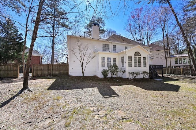 back of house featuring a chimney and fence