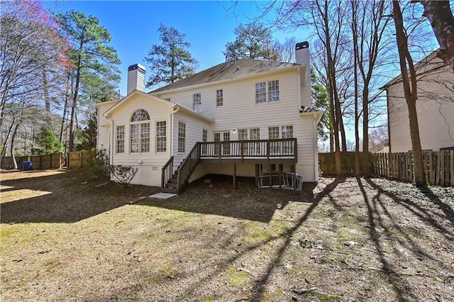 back of property with stairway, a chimney, a deck, and fence