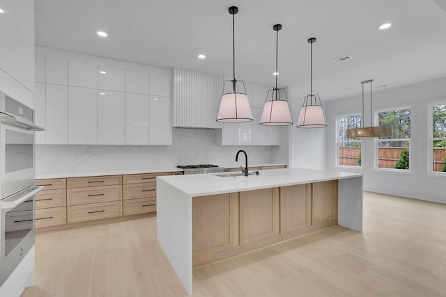 315 Hillcrest View Dr, Suwanee, GA 30024 - kitchen featuring light wood-style floors, a sink, decorative backsplash, modern cabinets, and light countertops