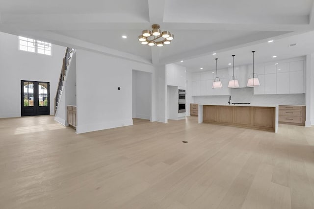 315 Hillcrest View Dr, Suwanee, GA 30024 - unfurnished living room with recessed lighting, light wood-type flooring, beam ceiling, a chandelier, and french doors