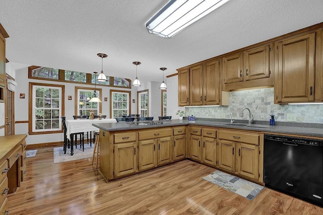kitchen featuring black appliances, a sink, dark countertops, light wood-style floors, and a textured ceiling