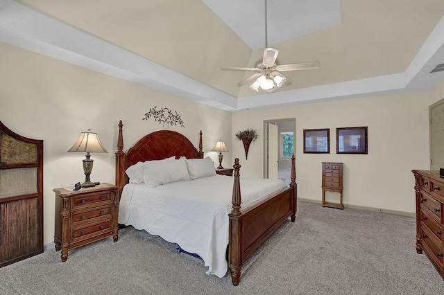 bedroom featuring light colored carpet, a tray ceiling, baseboards, and ceiling fan