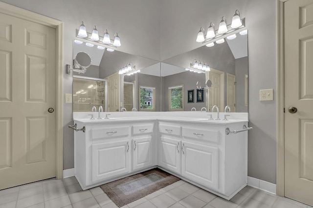full bath featuring baseboards, double vanity, a shower, and tile patterned flooring