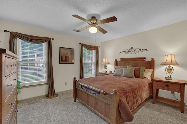 bedroom with light carpet, multiple windows, baseboards, ceiling fan, and a textured ceiling