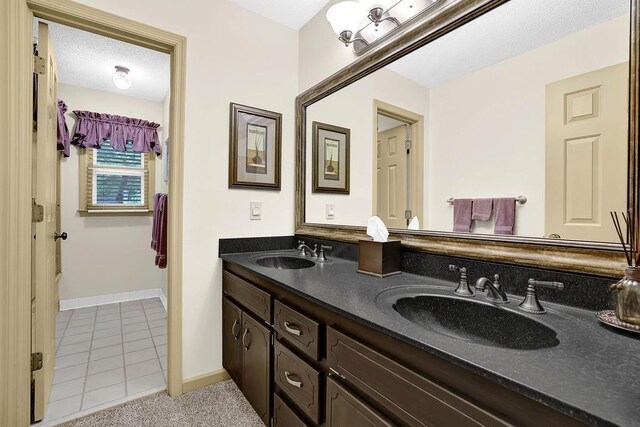 full bathroom with double vanity, tile patterned floors, and baseboards