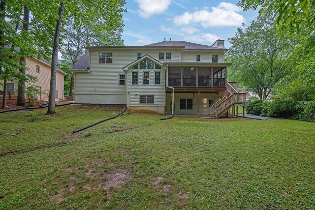 back of property featuring a sunroom, a chimney, stairs, and a yard