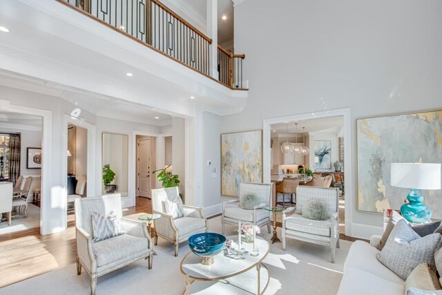 living room featuring crown molding, a towering ceiling, and light wood-type flooring