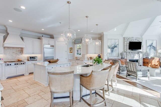 kitchen featuring pendant lighting, a breakfast bar, kitchen peninsula, appliances with stainless steel finishes, and custom range hood