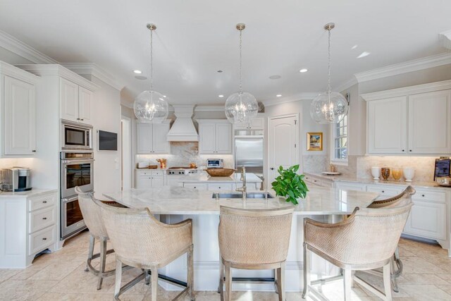 kitchen with custom range hood, white cabinetry, a spacious island, and sink