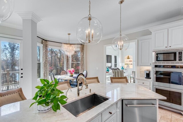 kitchen with sink, light stone counters, white cabinetry, stainless steel appliances, and a chandelier