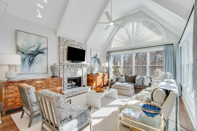 living room featuring ceiling fan, high vaulted ceiling, beamed ceiling, a fireplace, and hardwood / wood-style flooring