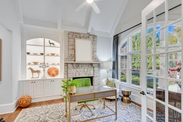 sunroom with a fireplace, ceiling fan, plenty of natural light, and lofted ceiling with beams