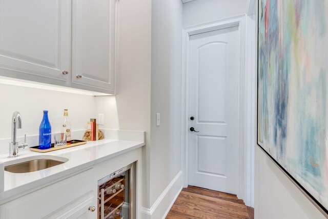 bar with white cabinets, light wood-type flooring, sink, and wine cooler