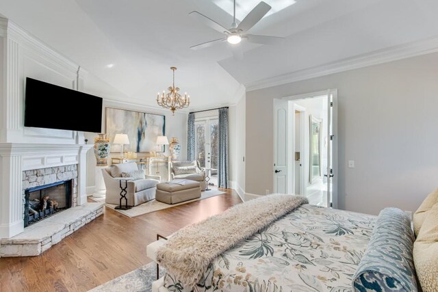 bedroom featuring a stone fireplace, crown molding, a notable chandelier, and hardwood / wood-style flooring