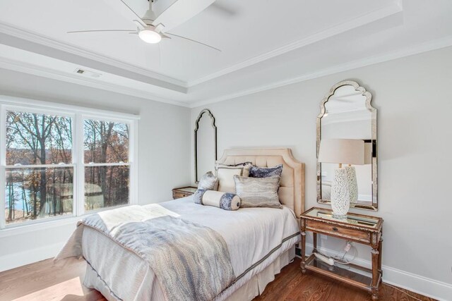 bedroom with a tray ceiling, ceiling fan, crown molding, and hardwood / wood-style flooring