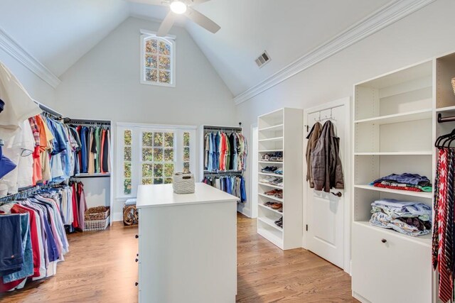 spacious closet with light hardwood / wood-style floors, high vaulted ceiling, and ceiling fan