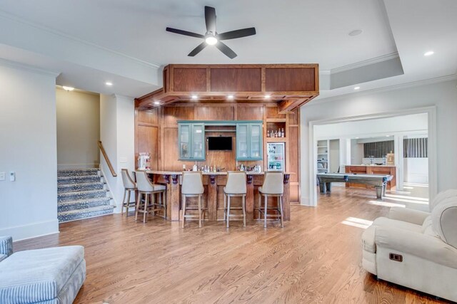 kitchen featuring a breakfast bar, light hardwood / wood-style floors, crown molding, and billiards