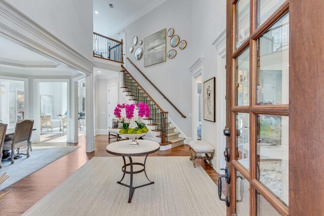 foyer entrance with hardwood / wood-style flooring, ornamental molding, and a high ceiling