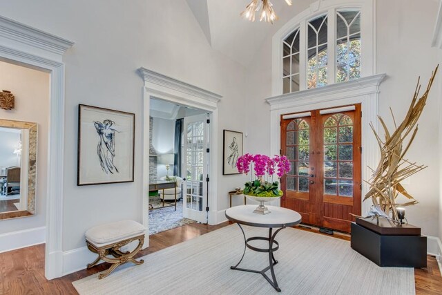 entryway featuring french doors, high vaulted ceiling, wood-type flooring, and an inviting chandelier