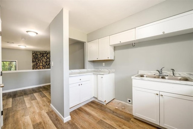 clothes washing area with baseboards, a sink, and light wood-style floors