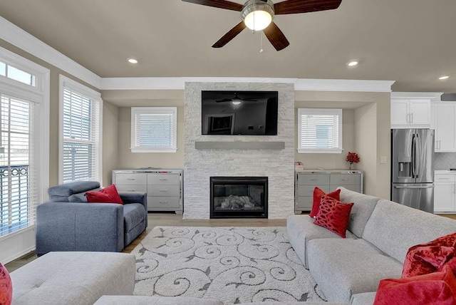 living room featuring light hardwood / wood-style flooring, a stone fireplace, and a wealth of natural light