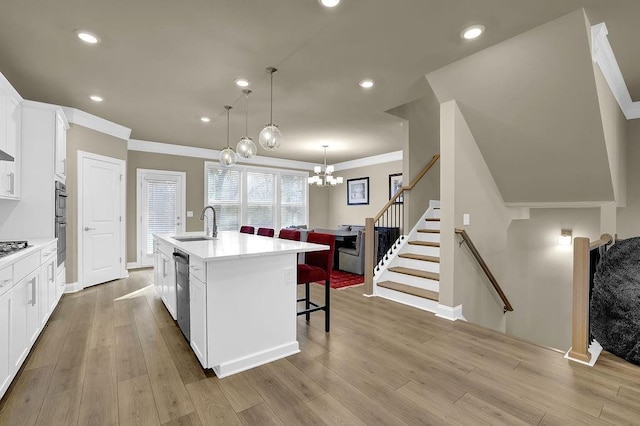 kitchen featuring sink, white cabinetry, a kitchen island with sink, pendant lighting, and light hardwood / wood-style floors