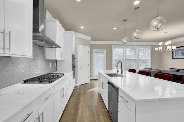 kitchen featuring pendant lighting, sink, appliances with stainless steel finishes, a kitchen island with sink, and wall chimney exhaust hood