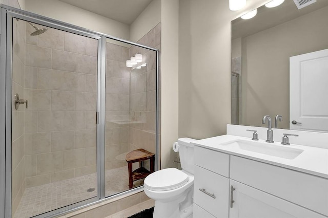 bathroom featuring vanity, a shower with door, and toilet