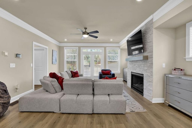 living room with crown molding, a stone fireplace, and light wood-type flooring