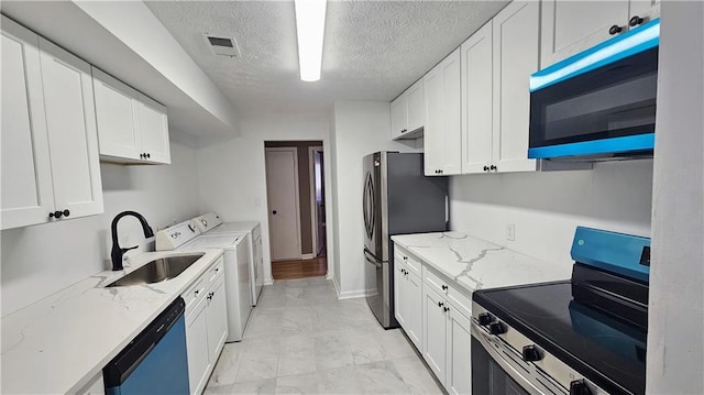 2388 Lawrenceville Hwy Unit D, Decatur, GA 30033 - kitchen with a textured ceiling, separate washer and dryer, white cabinets, appliances with stainless steel finishes, and light stone counters