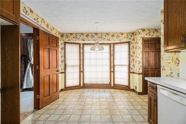 kitchen featuring a textured ceiling, light floors, dishwasher, and wallpapered walls