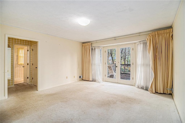 spare room featuring carpet, french doors, baseboards, and a textured ceiling