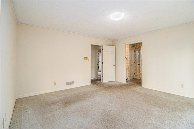 carpeted empty room featuring crown molding, baseboards, visible vents, and a textured ceiling