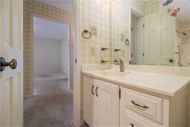 bathroom featuring baseboards, vanity, and wallpapered walls