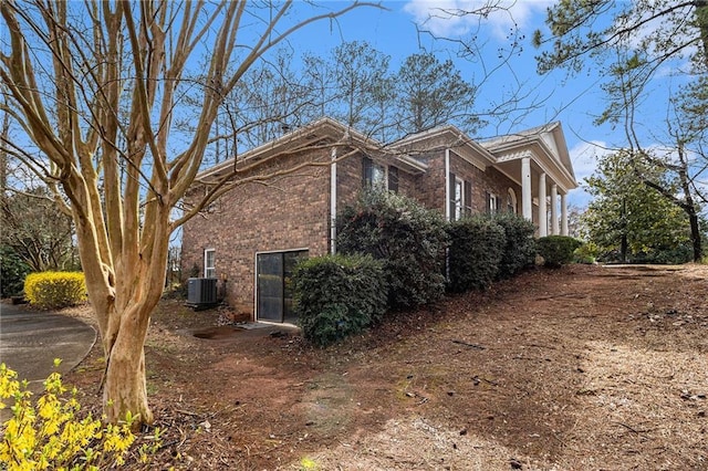 view of side of property with brick siding and central AC unit