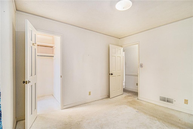 unfurnished bedroom featuring visible vents, a walk in closet, a closet, carpet floors, and baseboards