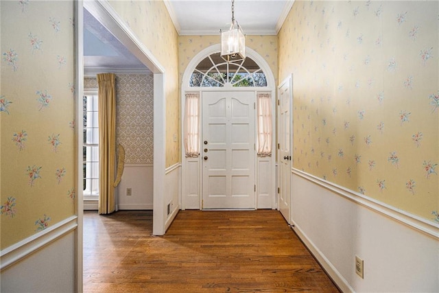 entrance foyer with wood finished floors, baseboards, wallpapered walls, ornamental molding, and a chandelier